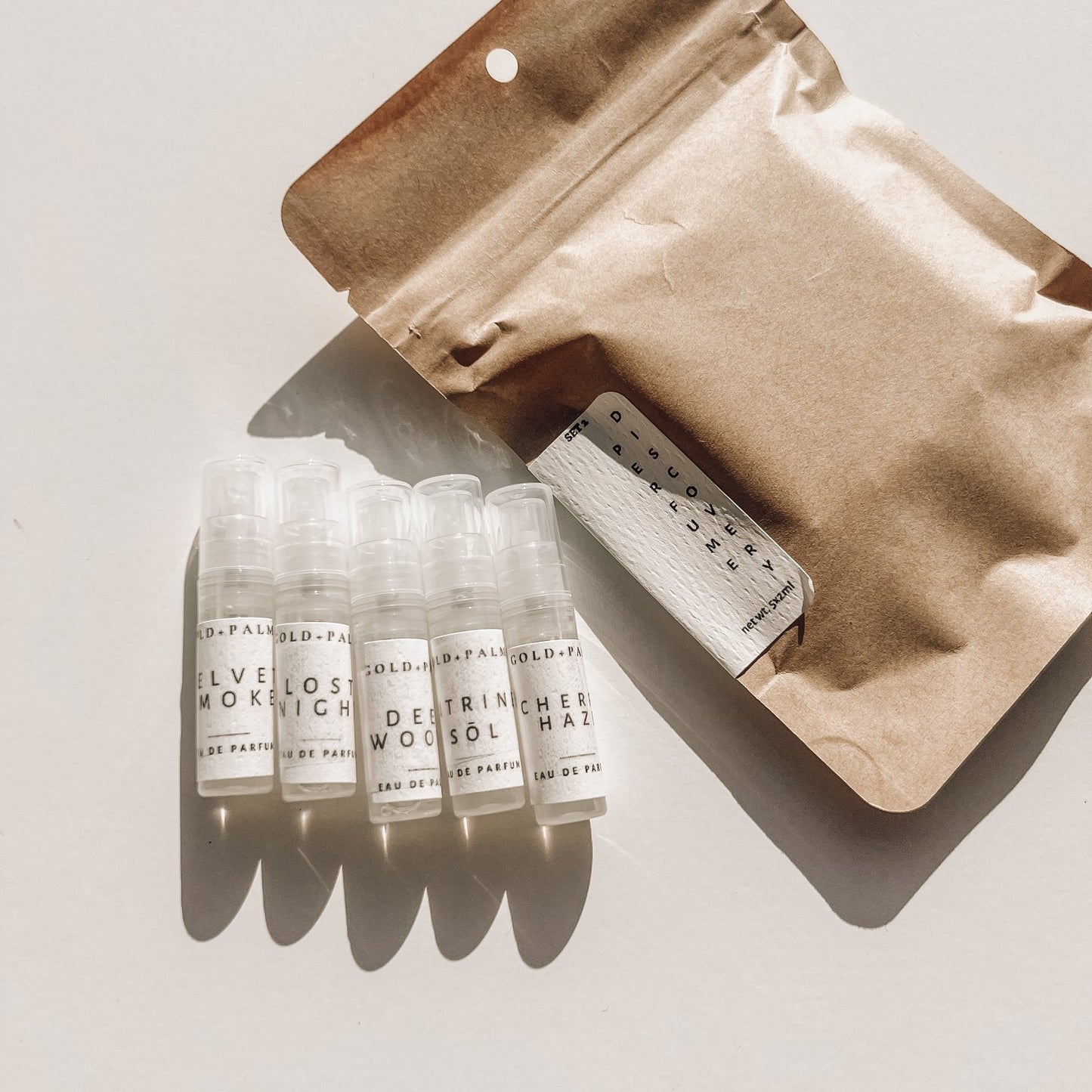 Gold and Palms Next 5 discovery set against white background with brown paper satchel packaging