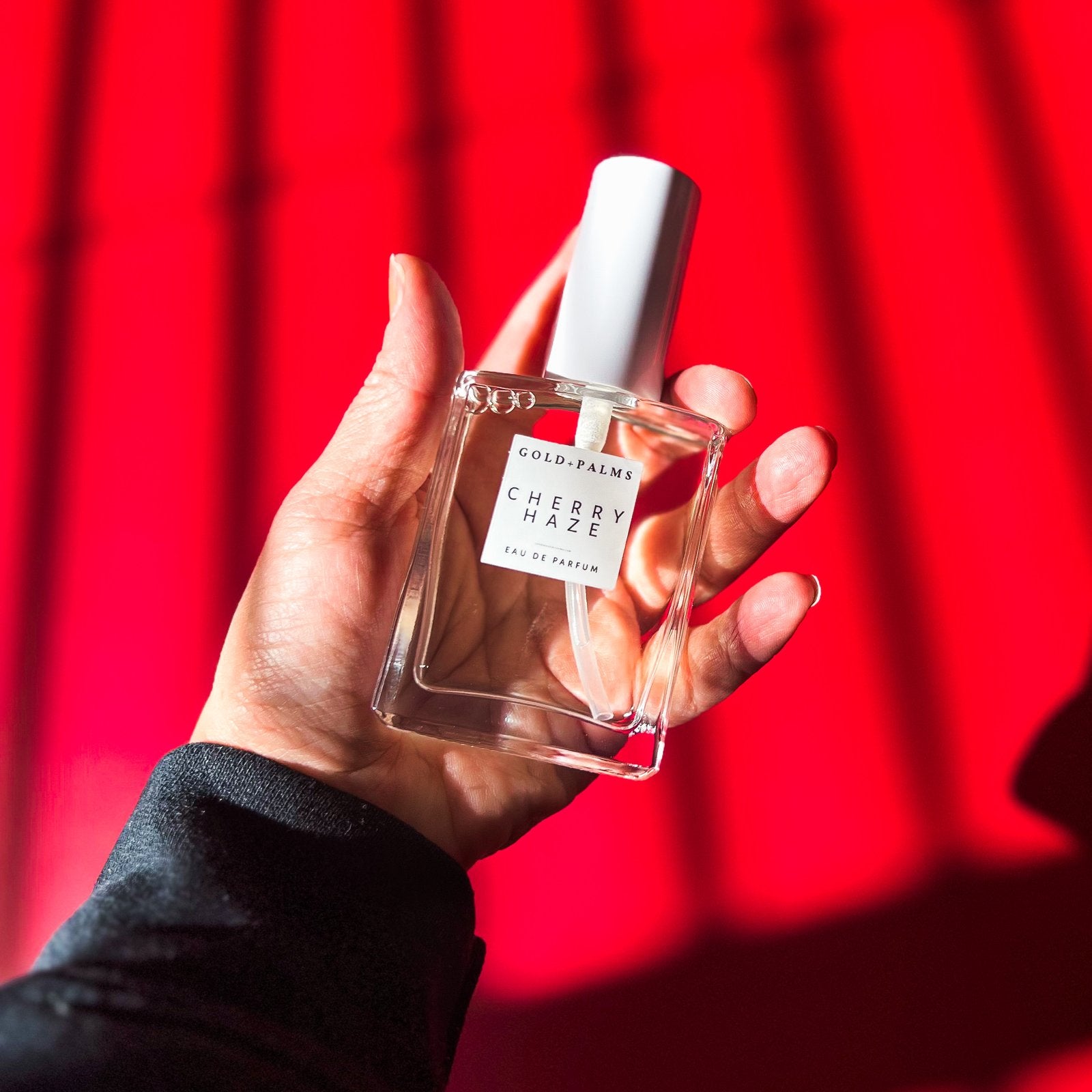 hand holding smokey cherry vanilla eau de parfum 50ml ml with red background