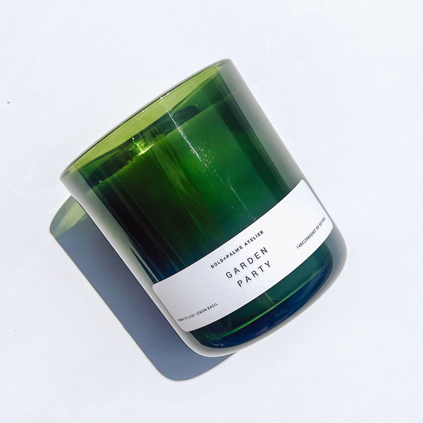 Tomato leaf lemon basil soy wax candle in a green glass vessel with a white background