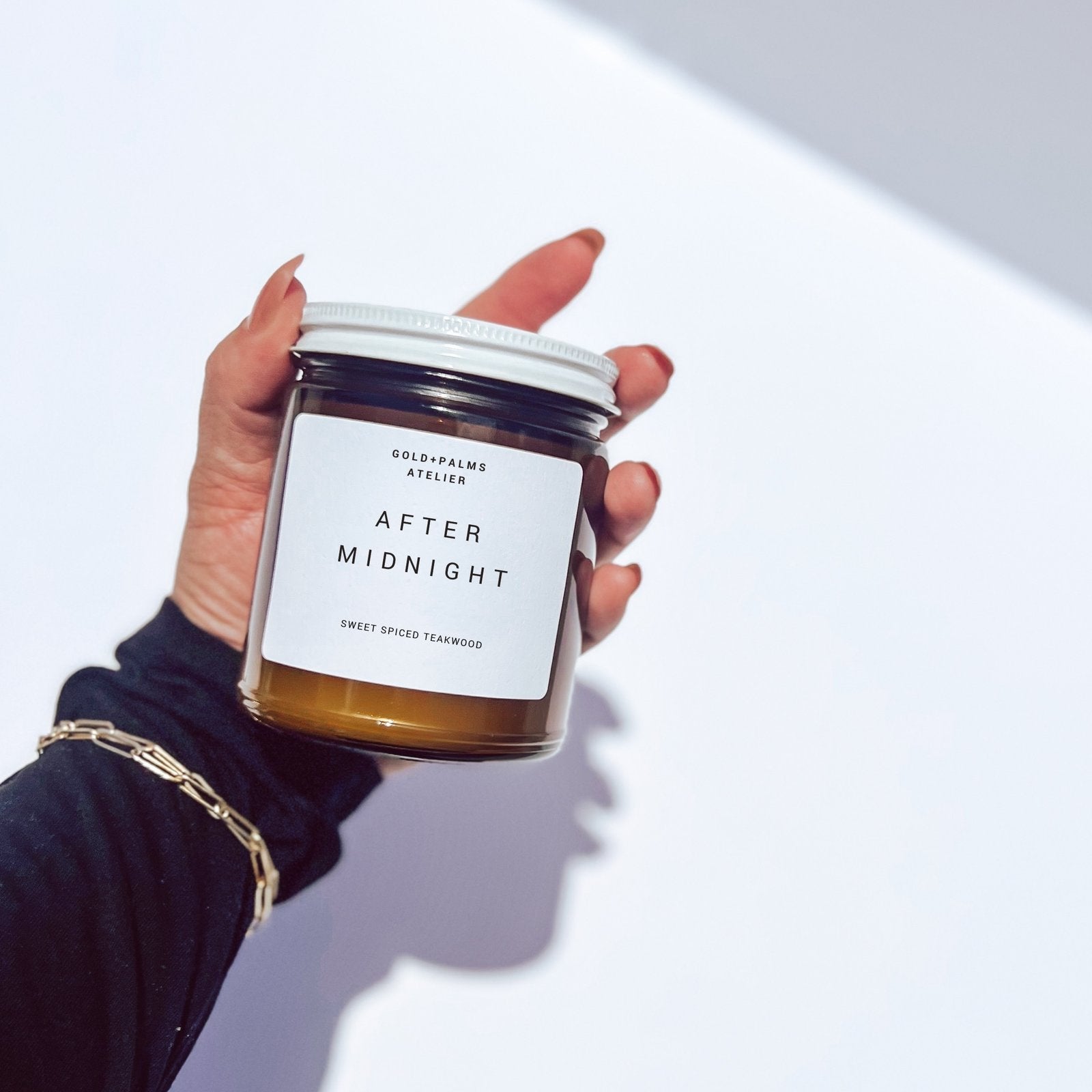 sweet spiced teakwood soy candle being held against a white background